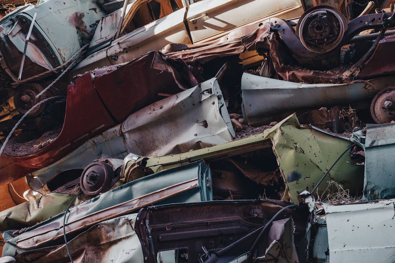 Close-up view of rusted cars stacked in a junkyard, showcasing decay and waste.
